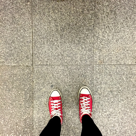 Closeup of Legs Wearing Black Jeans and Red Sneakers on Floor or Ground Background great for any use.の写真素材
