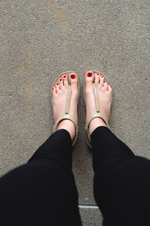 Female feet wearing slippers or flip-flop outdoor red nail great for any use.の写真素材