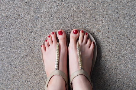 Female feet wearing slippers or flip-flop outdoor red nail great for any use.の写真素材