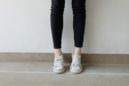 White sneakers on girl legs on ground background great for any use.の写真素材