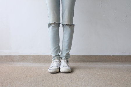 Young Fashion Woman's Legs in Blue Jeans and White Sneakers on Floor Great For Any Use.