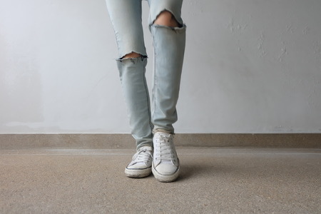 Young Fashion Woman's Legs in Blue Jeans and White Sneakers on Floor Great For Any Use.の写真素材