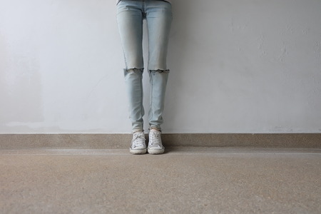 Young Fashion Woman's Legs in Blue Jeans and White Sneakers on Floor Great For Any Use.の写真素材