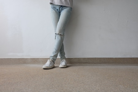 Young Fashion Woman's Legs in Blue Jeans and White Sneakers on Floor Great For Any Use.の写真素材