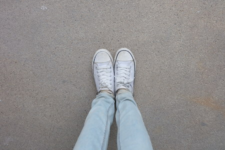 Young Fashion Woman's Legs in Blue Jeans and White Sneakers on Floor Great For Any Use.の写真素材