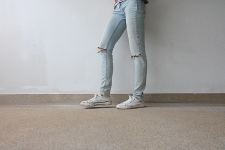 Young Fashion Woman's Legs in Blue Jeans and White Sneakers on Floor Great For Any Use.の写真素材