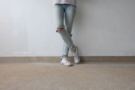 Young Fashion Woman's Legs in Blue Jeans and White Sneakers on Floor Great For Any Use.の写真素材