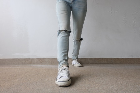 Young Fashion Woman's Legs in Blue Jeans and White Sneakers on Floor Great For Any Use.の写真素材