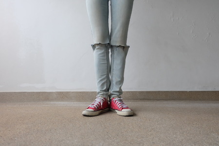 Young Fashion Woman's Legs in Blue Jeans and Red Sneakers on Floor Great For Any Use.の写真素材