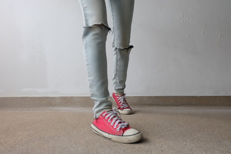 Young Fashion Woman's Legs in Blue Jeans and Red Sneakers on Floor Great For Any Use.の写真素材