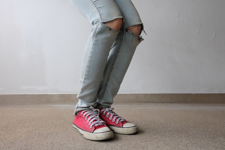 Young Fashion Woman's Legs in Blue Jeans and Red Sneakers on Floor Great For Any Use.の写真素材