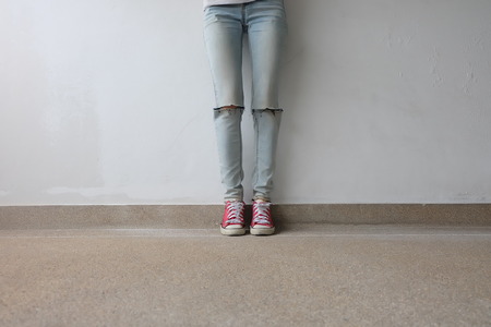Young Fashion Woman's Legs in Blue Jeans and Red Sneakers on Floor Great For Any Use.の写真素材