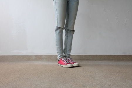 Young Fashion Woman's Legs in Blue Jeans and Red Sneakers on Floor Great For Any Use.の写真素材