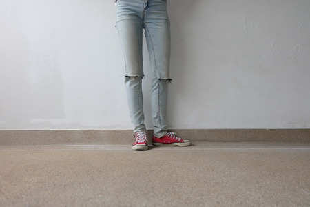 Young Fashion Woman's Legs in Blue Jeans and Red Sneakers on Floor Great For Any Use.の写真素材