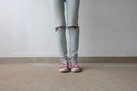 Young Fashion Woman's Legs in Blue Jeans and Red Sneakers on Floor Great For Any Use.の写真素材