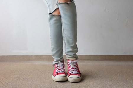 Young Fashion Woman's Legs in Blue Jeans and Red Sneakers on Floor Great For Any Use.の写真素材