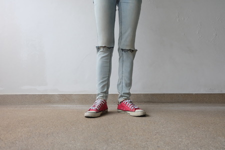 Young Fashion Woman's Legs in Blue Jeans and Red Sneakers on Floor Great For Any Use.の写真素材