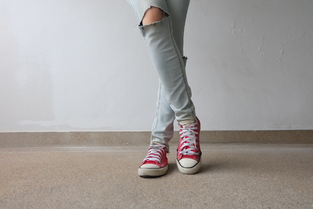 Young Fashion Woman's Legs in Blue Jeans and Red Sneakers on Floor Great For Any Use.の写真素材