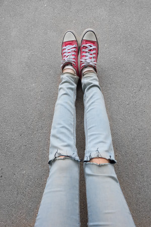 Young Fashion Woman's Legs in Blue Jeans and Red Sneakers on Floor Great For Any Use.