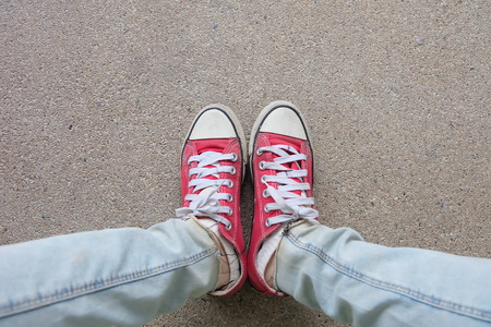 Young Fashion Woman's Legs in Blue Jeans and Red Sneakers on Floor Great For Any Use.の写真素材