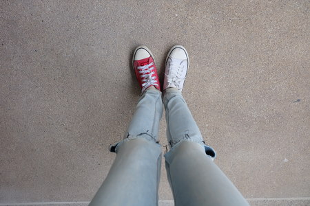 Young Fashion Woman's Legs in Blue Jeans and White, Red Sneakers on Floor Great For Any Use.の写真素材