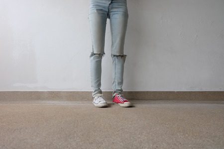 Young Fashion Woman's Legs in Blue Jeans and White, Red Sneakers on Floor Great For Any Use.の写真素材