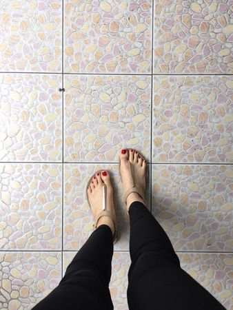 Female Legs Wearing Footwear Shoes or Flip-flop Outdoor Red Nail on Floor Background Great For Any Use.の写真素材