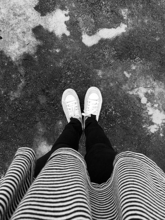 Young Fashion Woman's Legs With Black Jeans And White Sneakers On Cement Floor . White shoes Great For Any Use.の写真素材