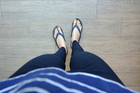 Young Girl Legs in Black Flipflop Sandals on Wood Floor Great For Any Use.