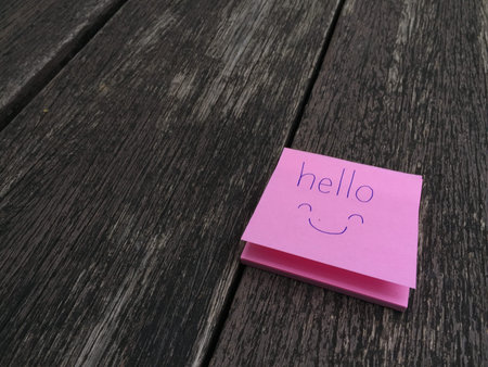 Hello Word Written on Pink Sticky Note on Wooden Background Great For Any Use.の写真素材