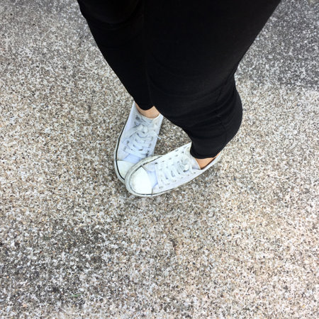 Young Fashion Woman's Legs with Sneakers, White Shoes on Floor Background Great For Any Use.