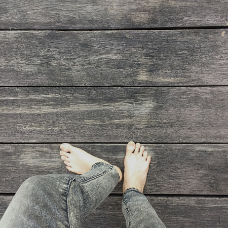 Woman's Jeans and Bare Feet on the Wooden Background Great For Any Use.の写真素材