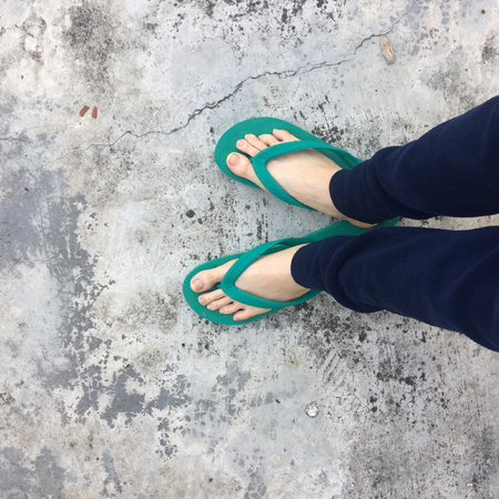 Feet of a Woman Wearing Green Sandals on the Old Concrete Floor Great For Any Use.の写真素材
