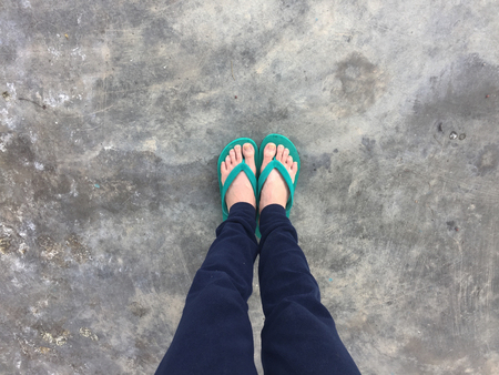 Feet of a Woman Wearing Green Sandals on the Old Concrete Floor Great For Any Use.の写真素材