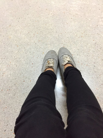 Young Fashion Woman's Legs in Black Jeans and Gray Sneakers on Floor Great For Any Use.