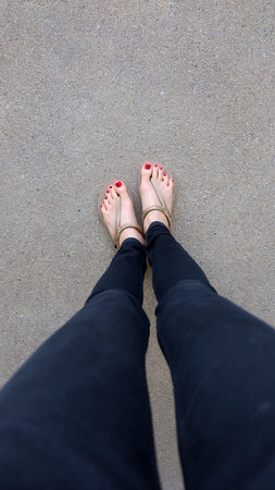 Close Up on Girl's Feet Wearing Golden Sandals on Ground Background Great For Any Use.