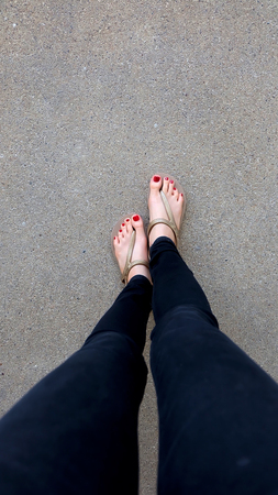 Close Up on Girl's Feet Wearing Golden Sandals on Ground Background Great For Any Use.の写真素材