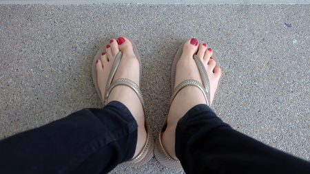 Close Up on Girl's Feet Wearing Golden Sandals on Ground Background Great For Any Use.の写真素材