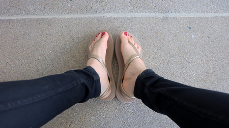 Close Up on Girl's Feet Wearing Golden Sandals on Ground Background Great For Any Use.の写真素材