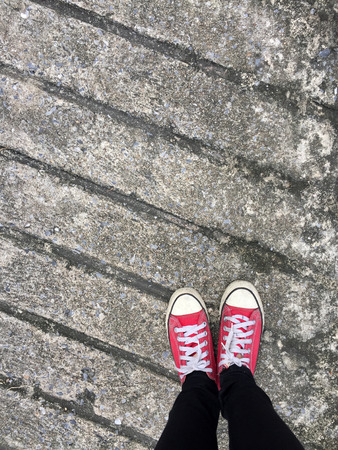 Closeup Photo of From Woman Wearing Red Sneakers On The Concrete Floor Background Great For Any Use.の写真素材