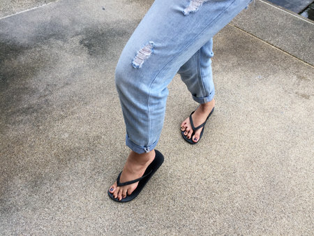 Close Up on Girl's Feet Wearing Black Sandals and Blue Jeans on the Street Great For Any Use.