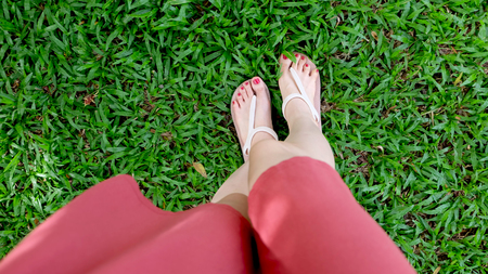 Close Up on Girl's Feet Wearing Sandals on Green Grass Great For Any Use.の写真素材