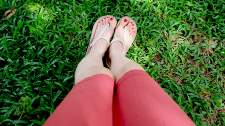 Close Up on Girl's Feet Wearing Sandals on Green Grass Great For Any Use.の写真素材