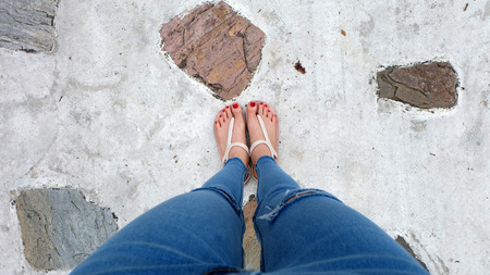 Close Up on Girl's Feet Wearing Sandals and Red Nail on The Cement Great For Any Use.の写真素材