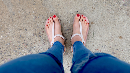 Close Up on Girl's Feet Wearing Sandals and Red Nail on Soil Background Great For Any Use.の写真素材