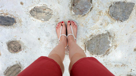Close Up on Girl's Feet Wearing Sandals and Red Nail on The Cement Great For Any Use.の写真素材