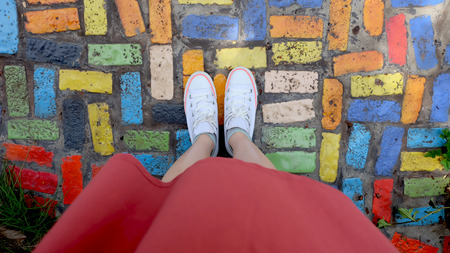 Close Up on Girl's Feet Wearing White Sneakers Standing on Coloful Tile Great For Any Use.の写真素材