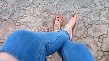 Close Up on Girl's Feet Wearing Sandals and Blue Jeans on The Tile Great For Any Use.の写真素材