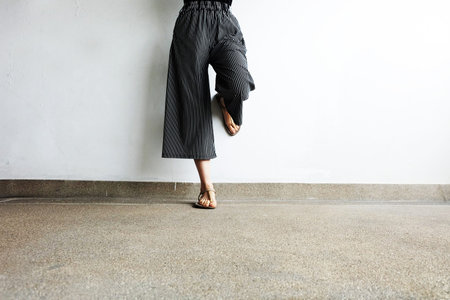 Feet Woman Wear Sandals and Black Pants. Female Standing on The Cement Background Great For Any Use.