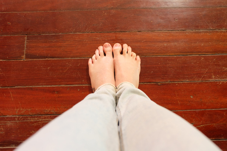 Close Up Woman Barefoot Wear Blue Jeans on Wooden Floor Background Great For Any Use.の写真素材